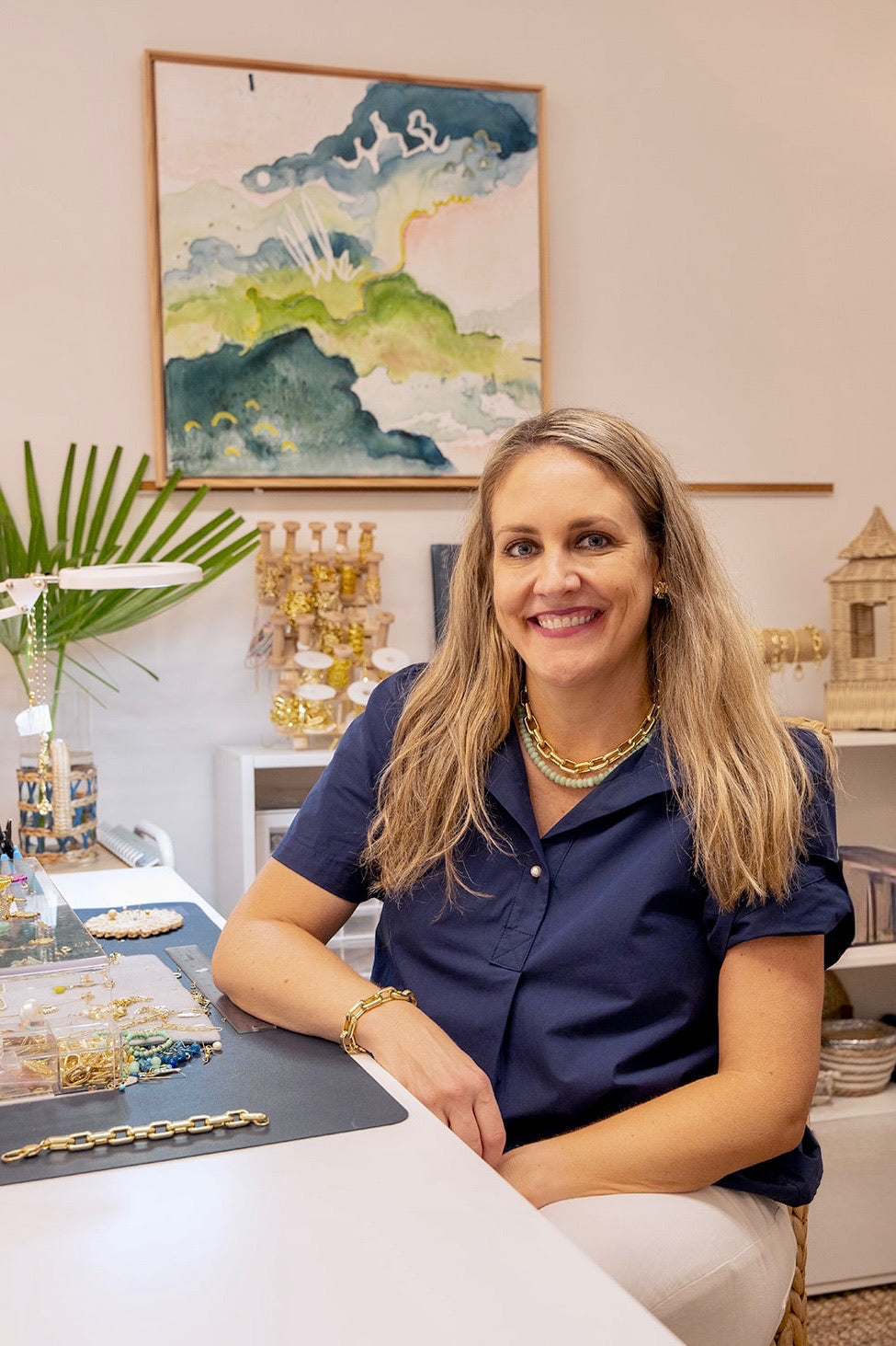 Woman sitting at a desk with decorative items and artwork in the background